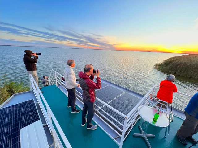Birdwatchers on upper sun deck of Ibis Tours floating hotel at sunset — Danube Delta wildlife cruise