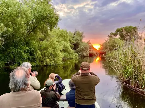 Wildlife photographers on a boat trip at sunset on a Danube Delta channel