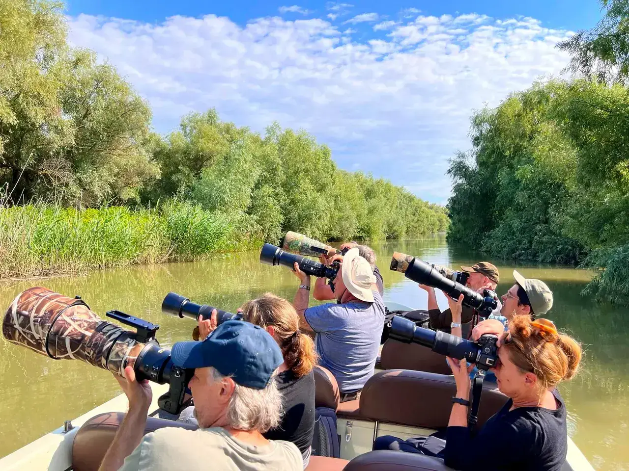 Wildlife photographers with telephoto lenses on boat in Danube Delta